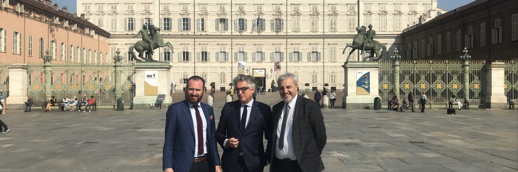 Tre uomini uno accanto all'altro in posa in Piazza Castello a Torino