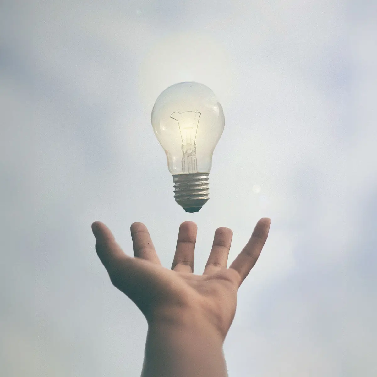 Una mano con a mezz'aria una lampadina accesa