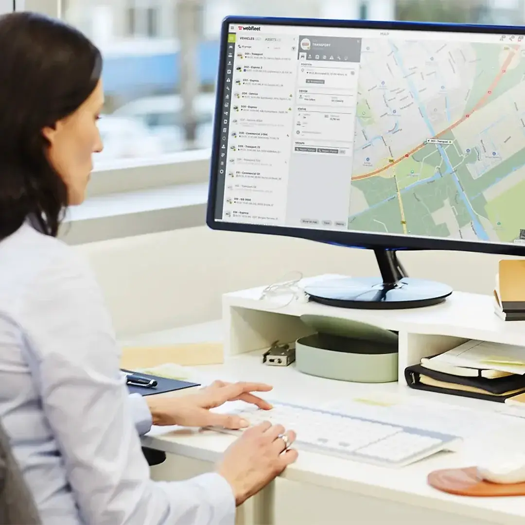 Una donna usa il computer e studia una mappa per la gestione della flotta.