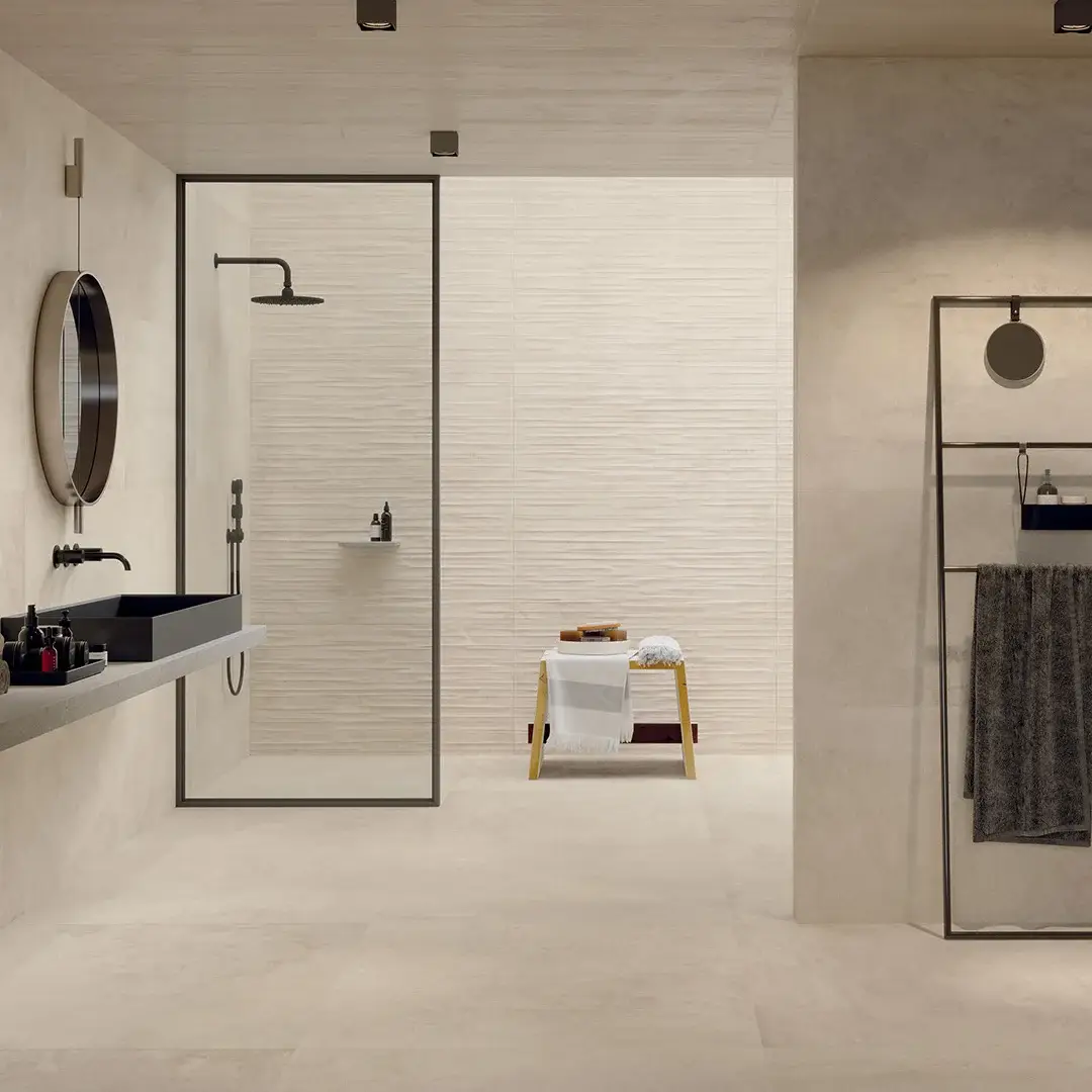 Bagno moderno: piastrelle beige, specchio rotondo, lavandino nero.
