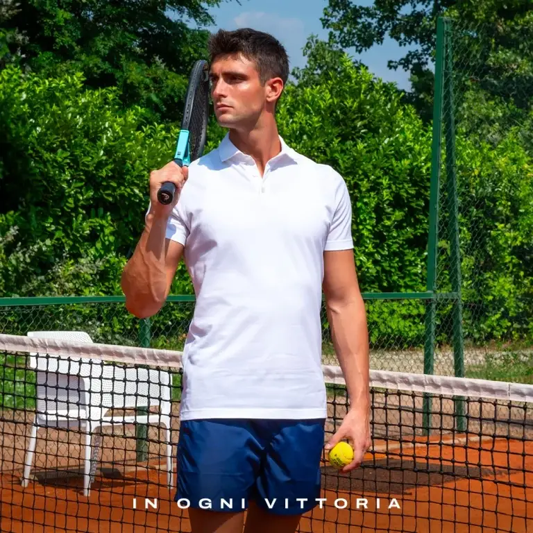 Modello con polo bianca e pantaloncini Julipet su un campo da tennis, con il testo "In ogni vittoria"