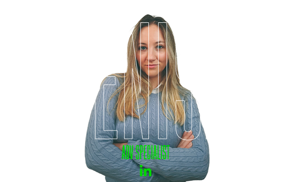 Donna bionda con maglione blu, braccia incrociate. DENISA, specialista UX.