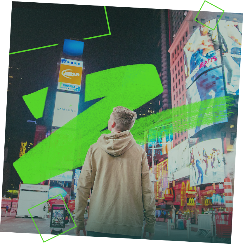 Persona con felpa con cappuccio abbronzata guarda gli annunci luminosi del Digitorium di Times Square.