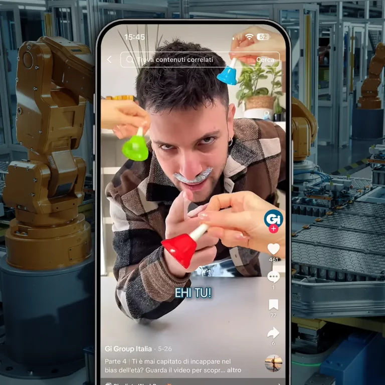 Uomo in videochiamata picchiato giocosamente con martelli giocattolo, robot alle spalle.