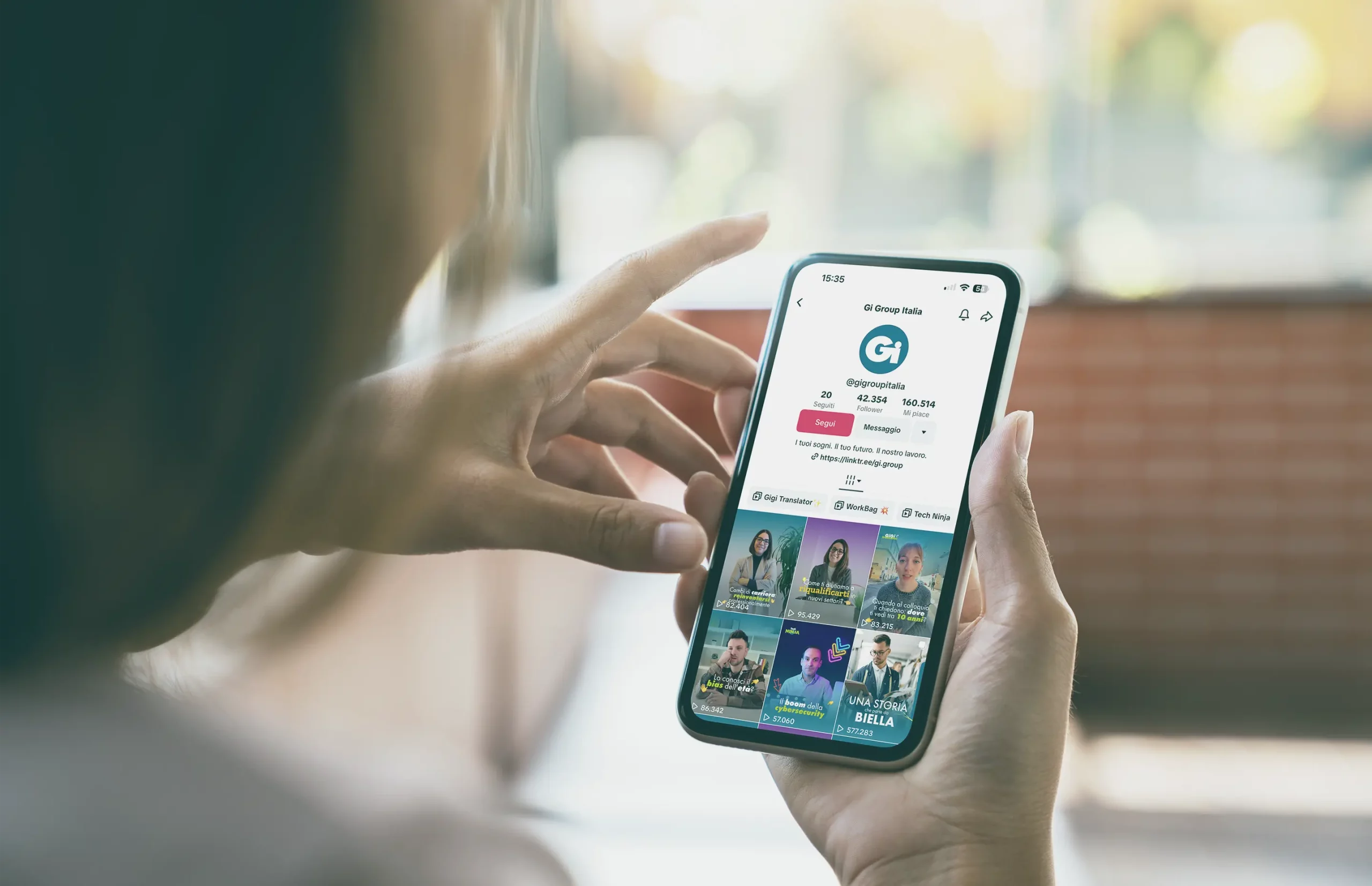 Person holds smartphone showing social profile in bright room.