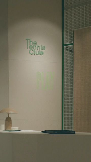 Showroom stile minimal con lampada, quaderno e logo sulla parete.
