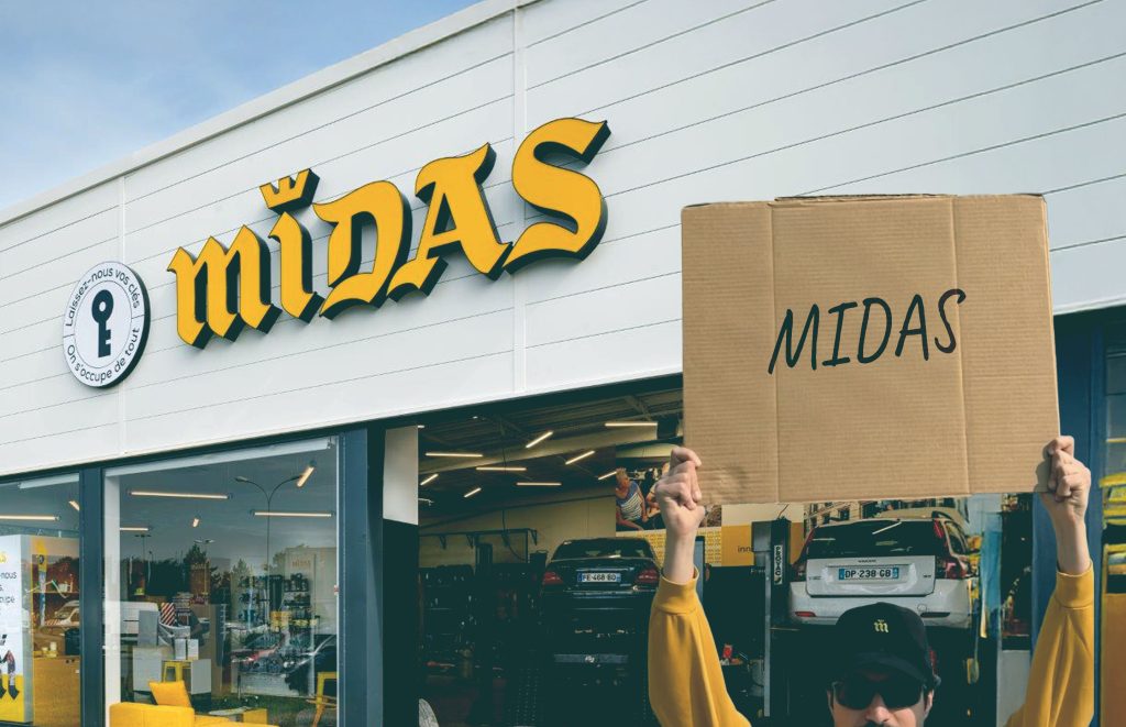 Persona che tiene in mano l'insegna MIDAS all'esterno dell'autofficina gialla Midas.