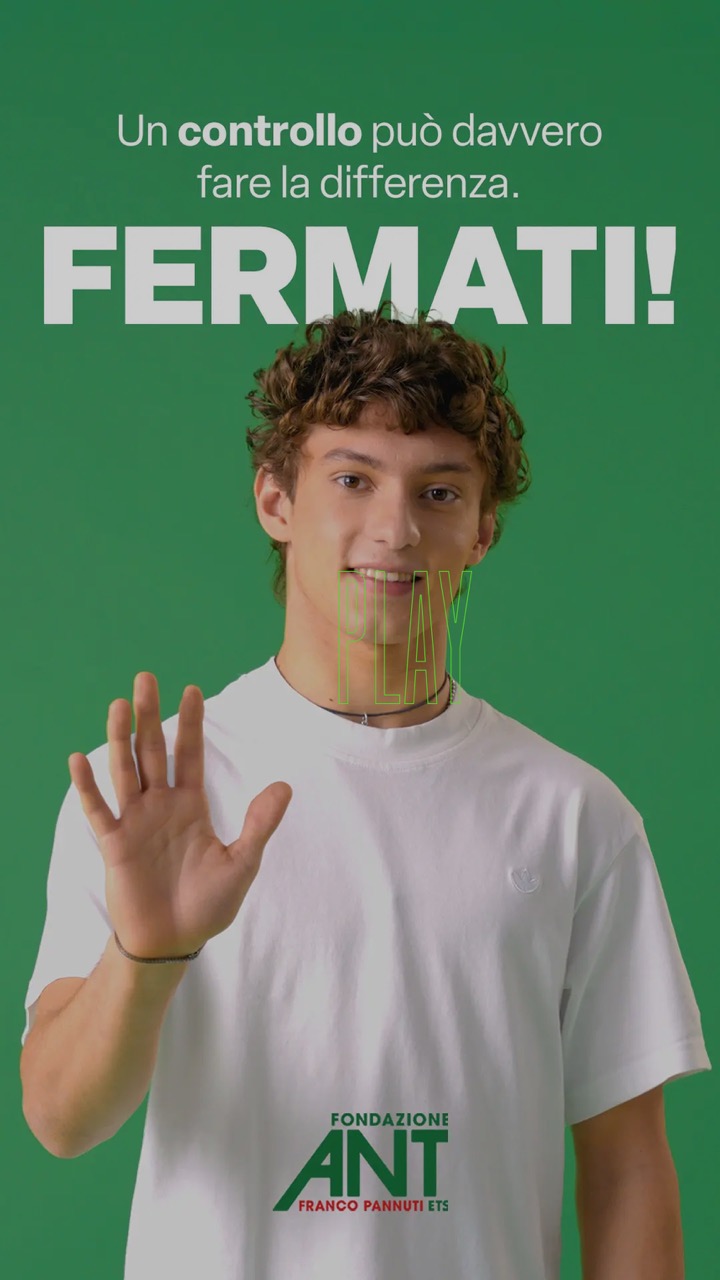 Kimi Antonelli con una maglietta bianca alza la mano davanti a uno sfondo verde con una scritta relativa alla salute.